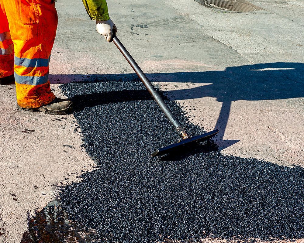 Worker Raking Asphalt on a Road – Oahu, HI – Oahu Sealcoating & Paving
