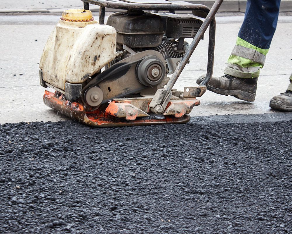 Worker Using a Machine to Compact Asphalt on a Road – Oahu, HI – Oahu Sealcoating & Paving
