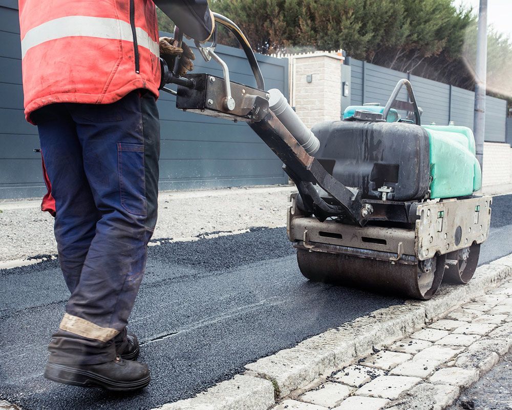 Worker Using a Machine to Roll Asphalt on a Road – Oahu, HI – Oahu Sealcoating & Paving
