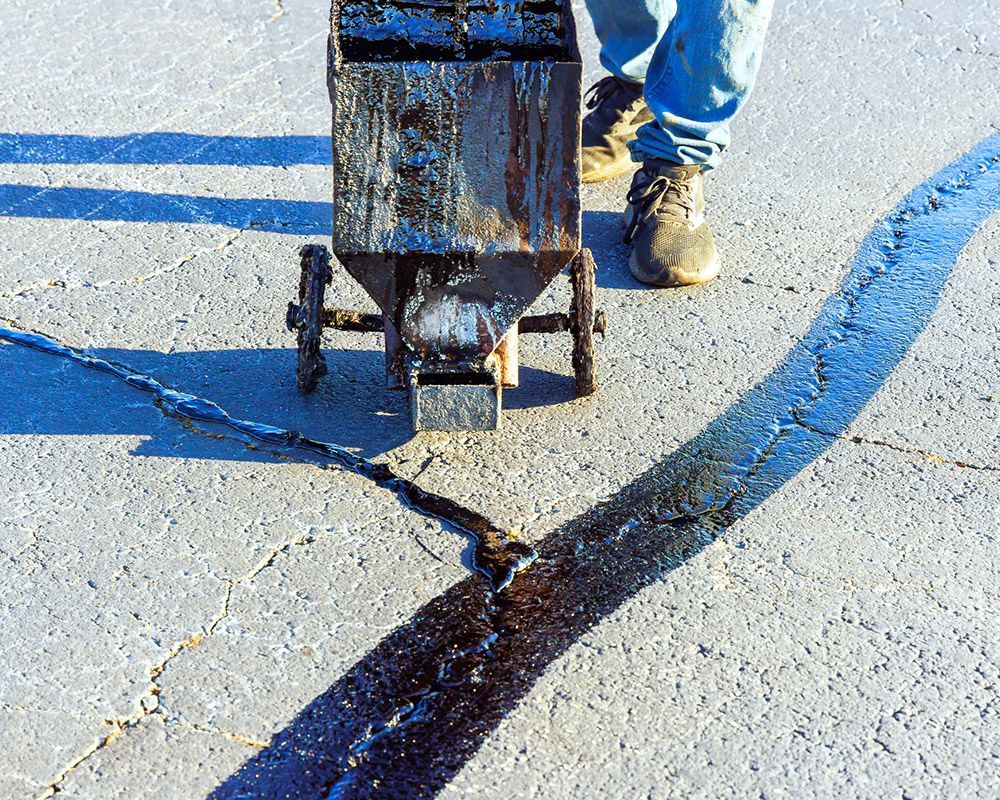 Worker Using Asphalt to Seal Road Crack – Oahu, HI – Oahu Sealcoating & Paving