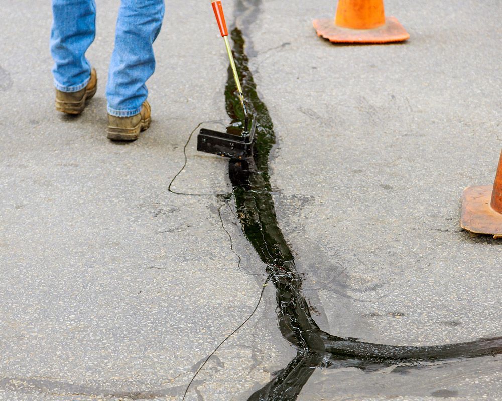 Worker Using Hot Asphalt to Seal Parking Lot Crack – Oahu, HI – Oahu Sealcoating & Paving
