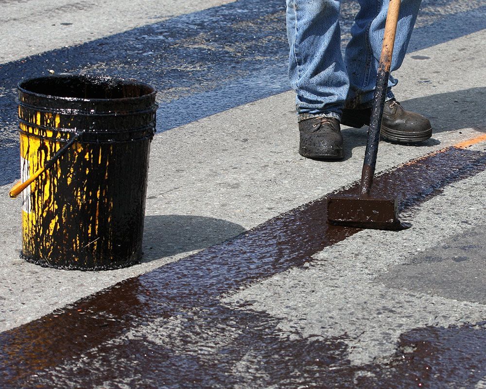 Worker Standing Next to a Bucket of Asphalt – Oahu, HI – Oahu Sealcoating & Paving