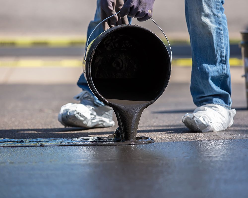Worker Pouring Asphalt from a Bucket onto the Ground – Oahu, HI – Oahu Sealcoating & Paving