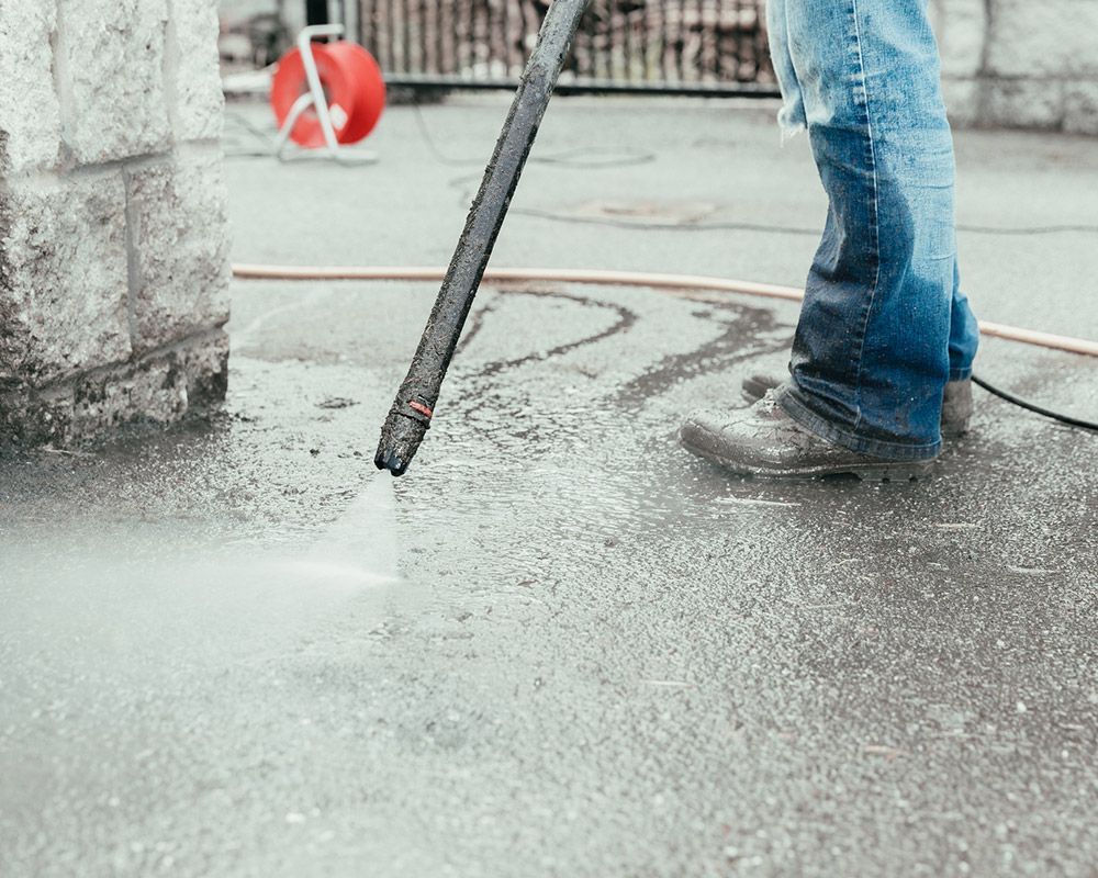 Worker Using Pressure Washer to Remove Road Debris – Oahu, HI – Oahu Sealcoating & Paving