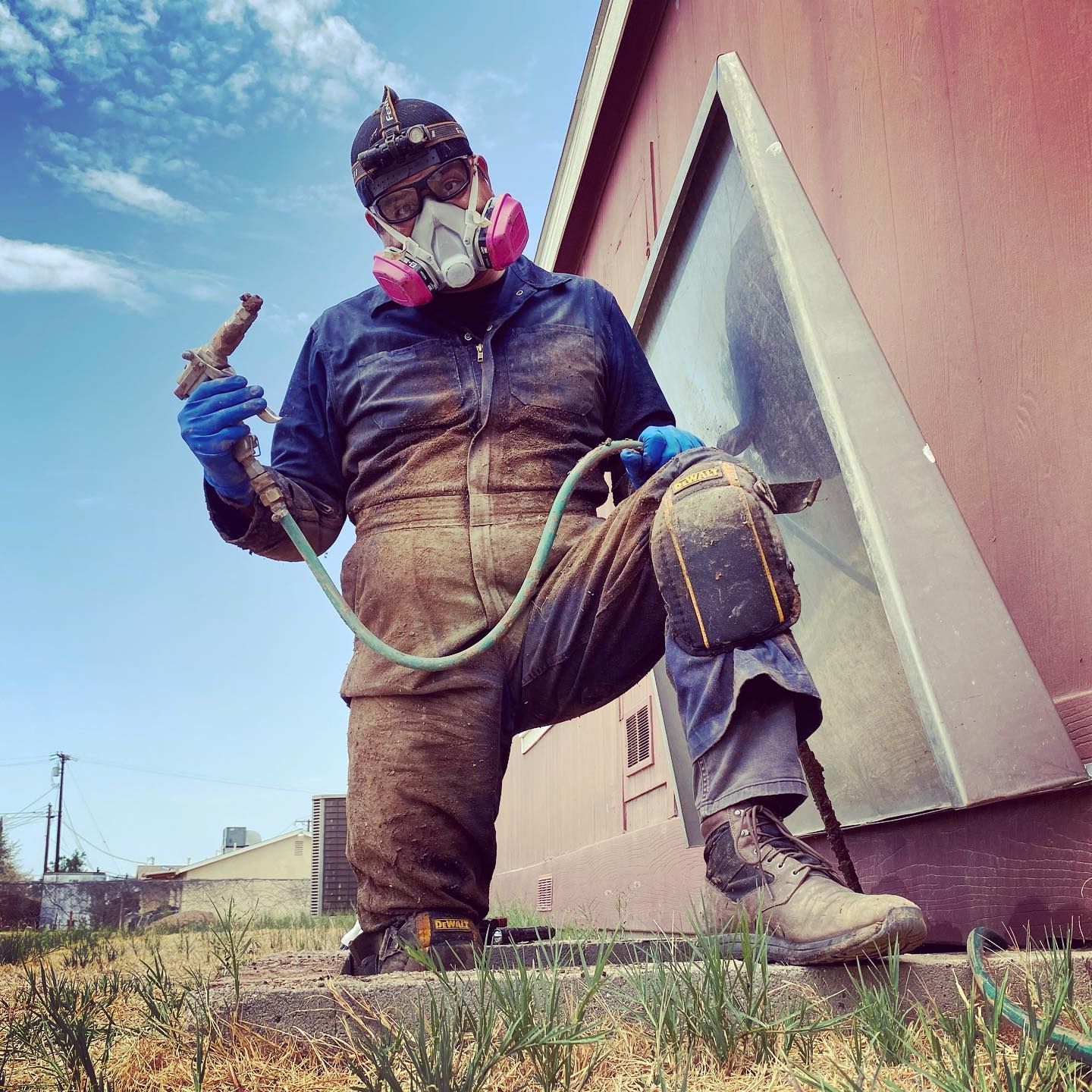 A man wearing a gas mask is kneeling in front of a building