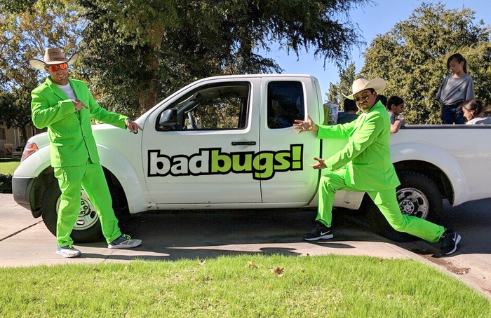 two men pointing at a white truck that says badbugs!