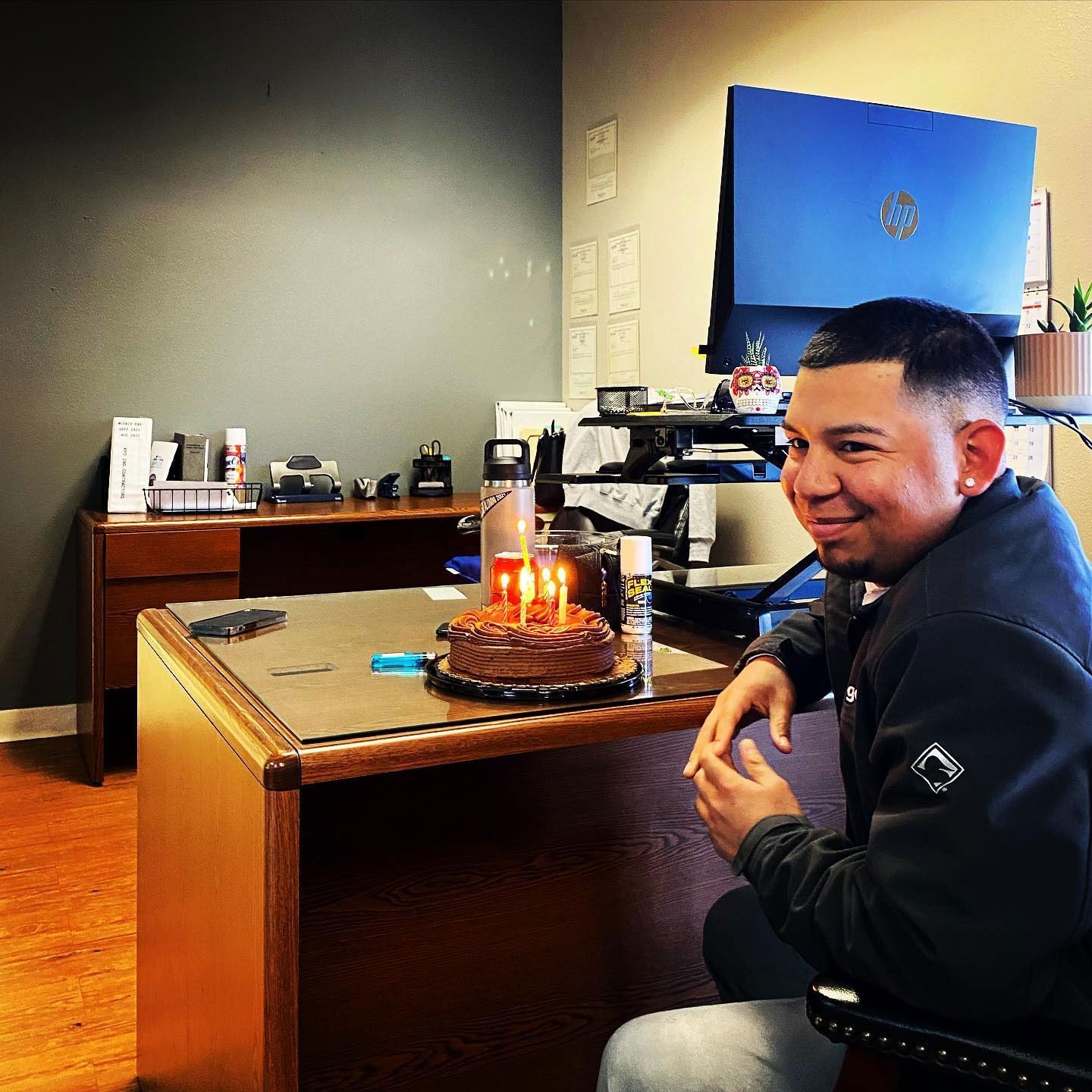 A man sits at a desk in badbugs! with a cake