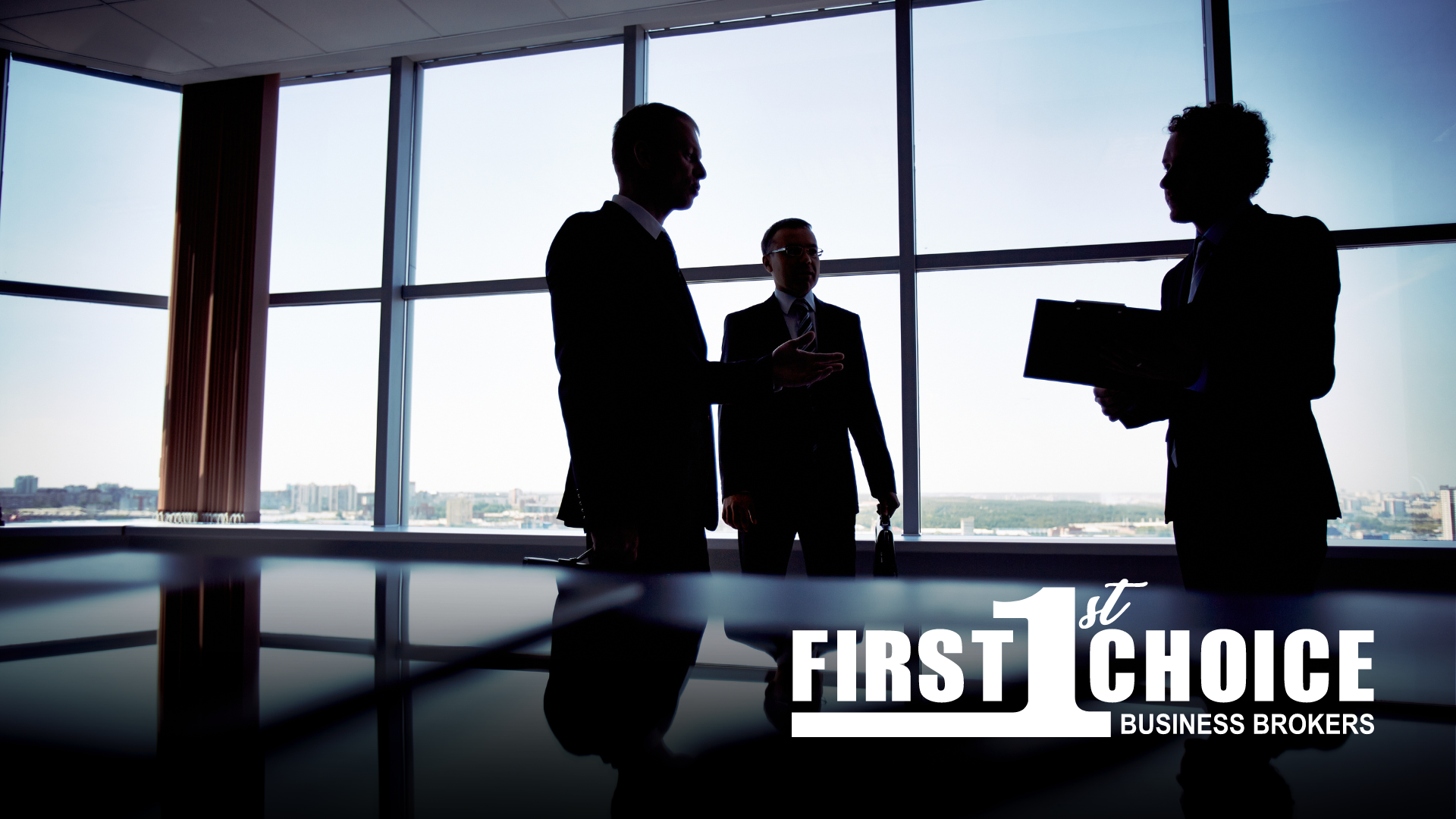 A group of business people are standing around a table holding papers.