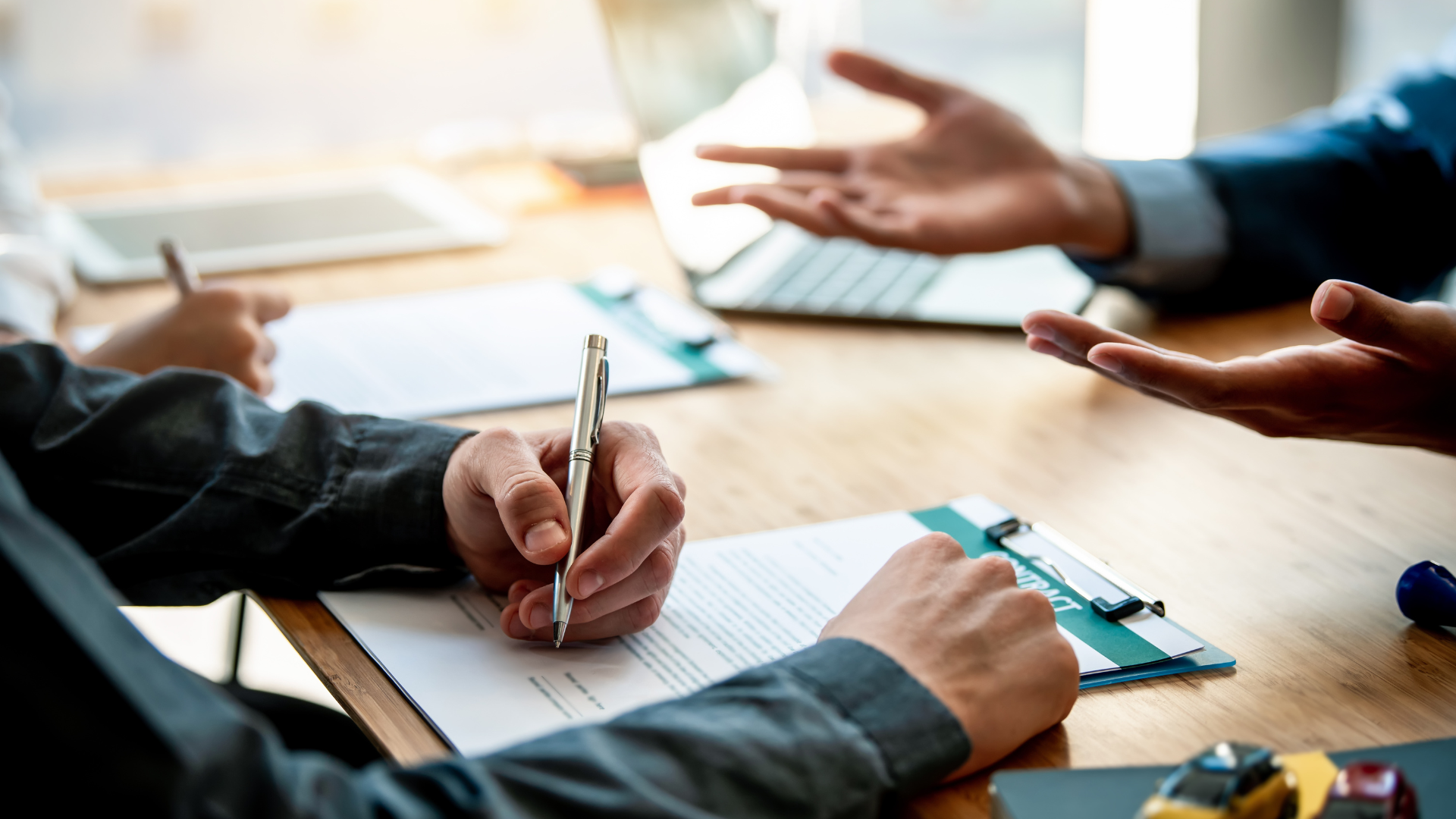 A man is writing on a piece of paper while another man talks to him.