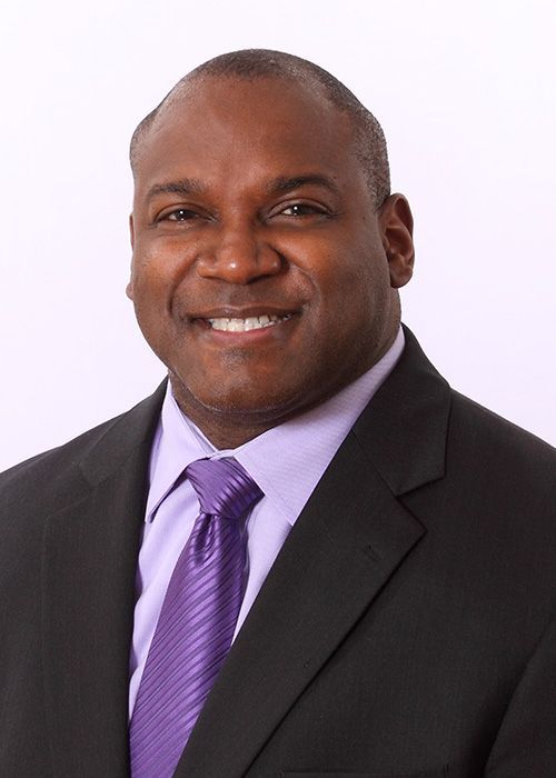 A man in a suit and tie is smiling for the camera
