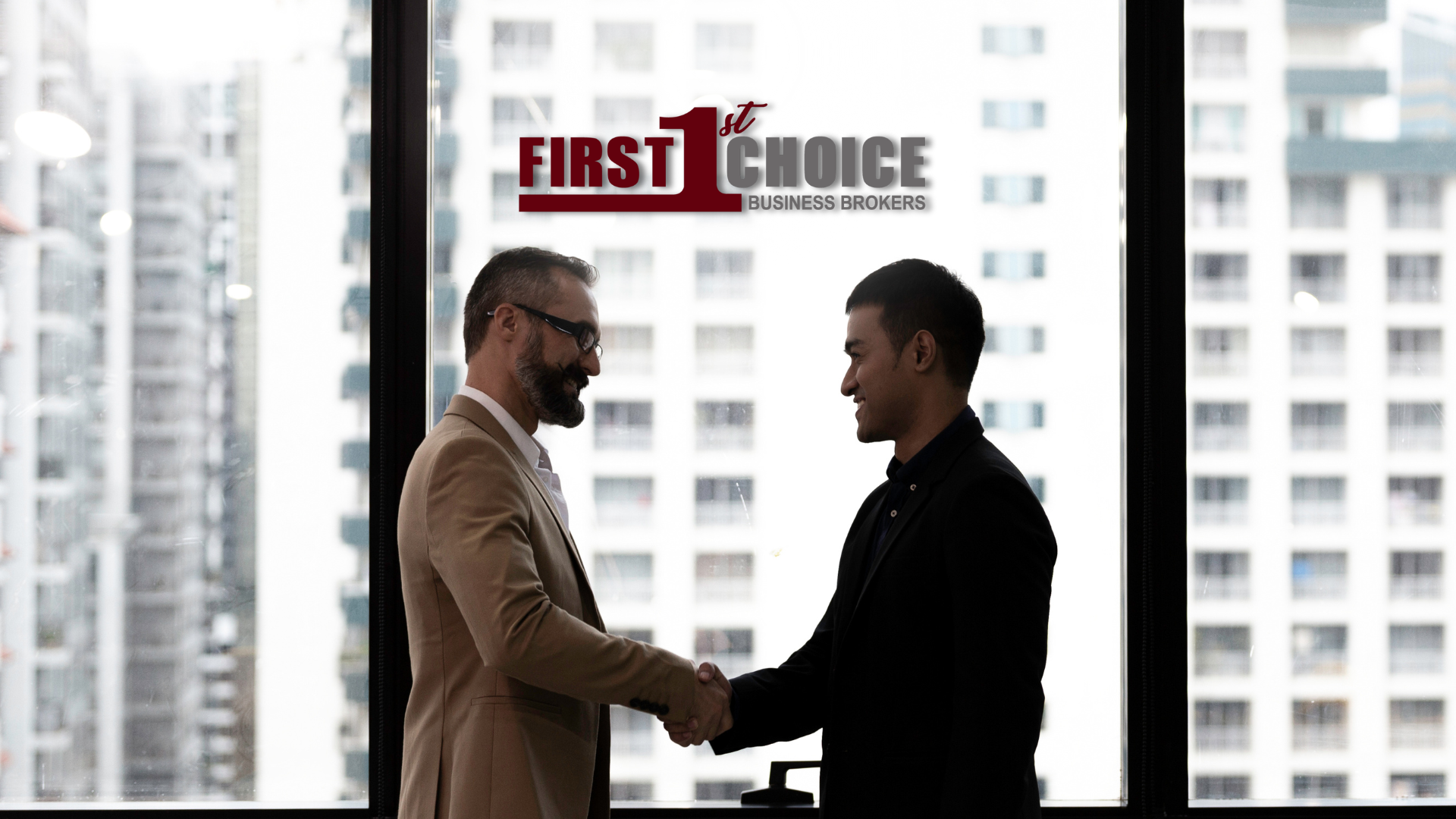 Two men are shaking hands in front of a window.