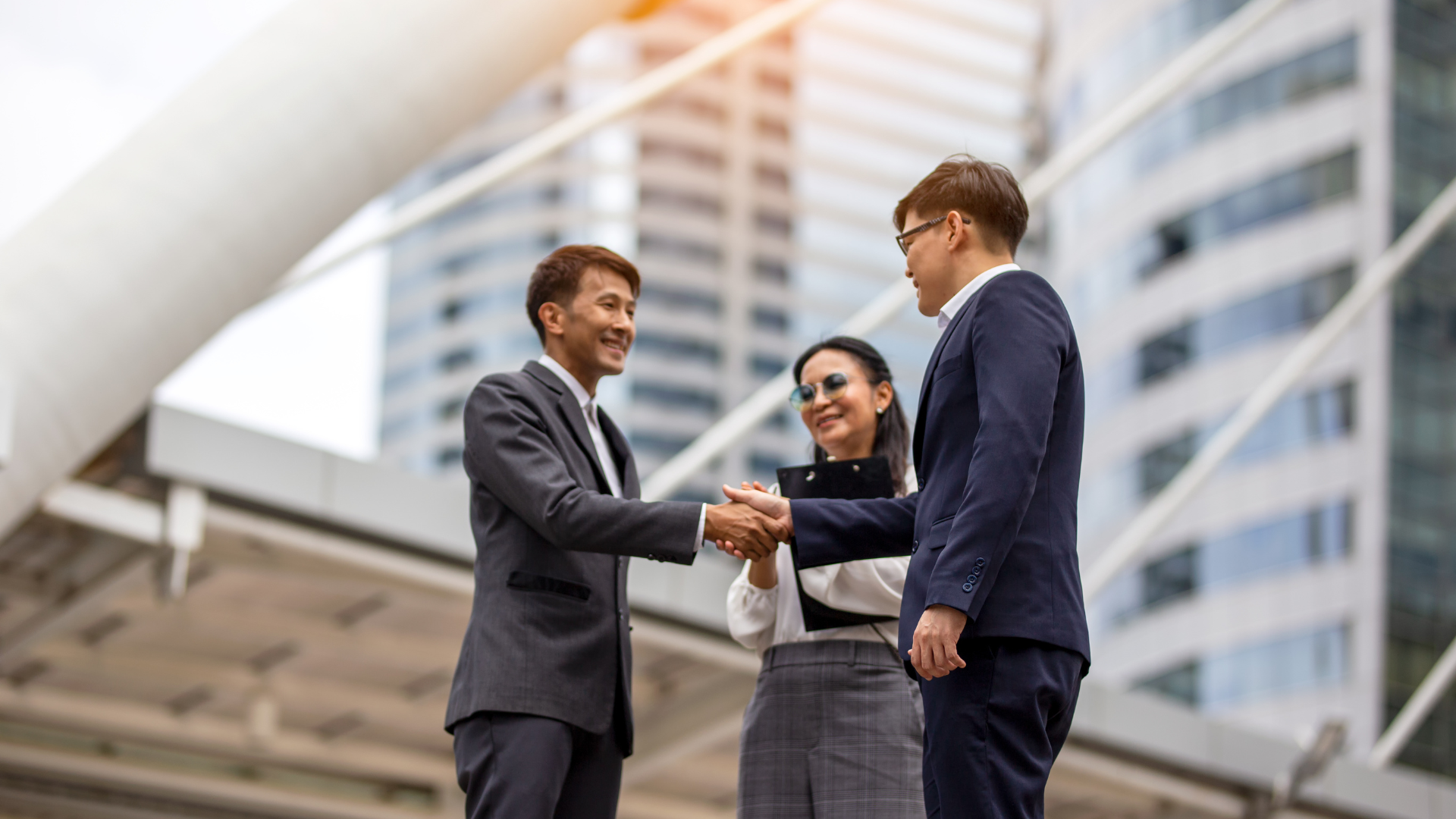 A group of business people shaking hands in front of a building.