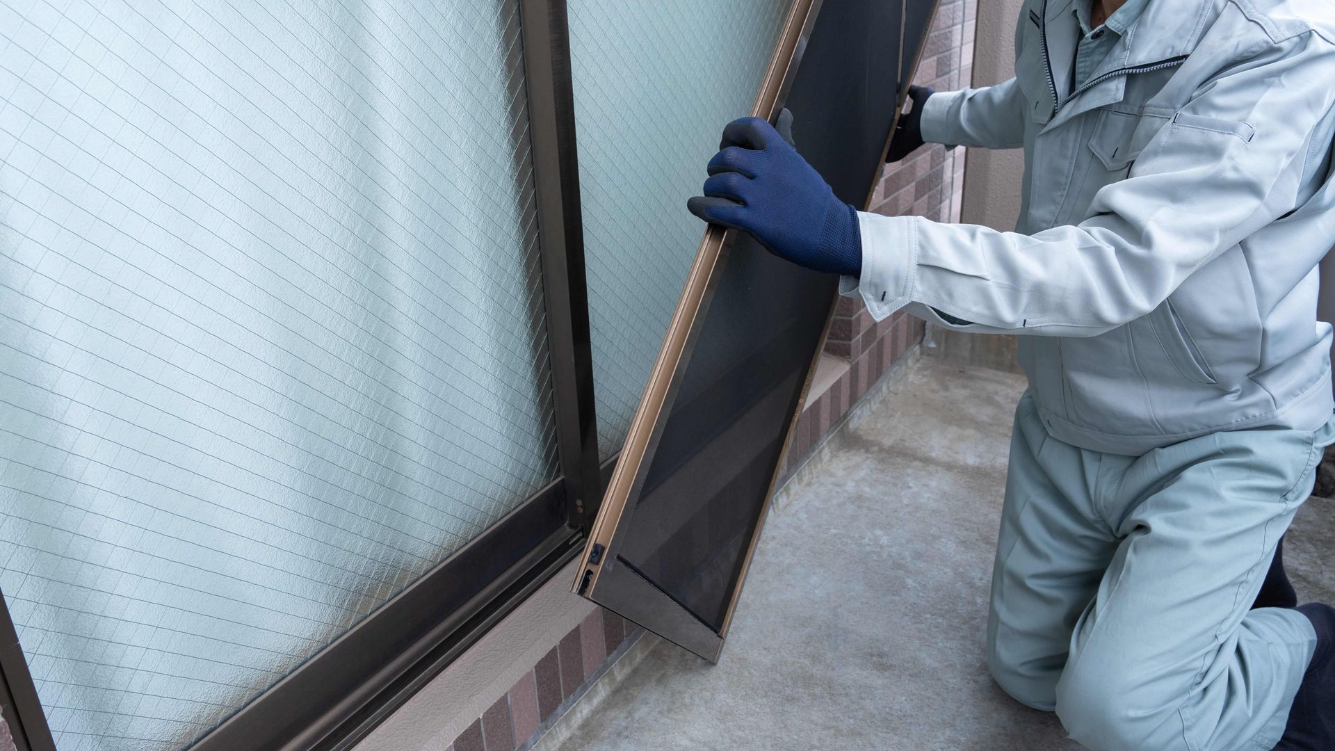 Person installing a new screen on a home's screen door