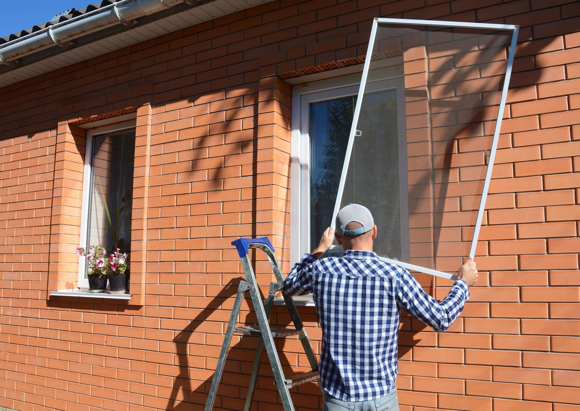 Man performing a mobile window screen replacement service on a home in Los Angeles