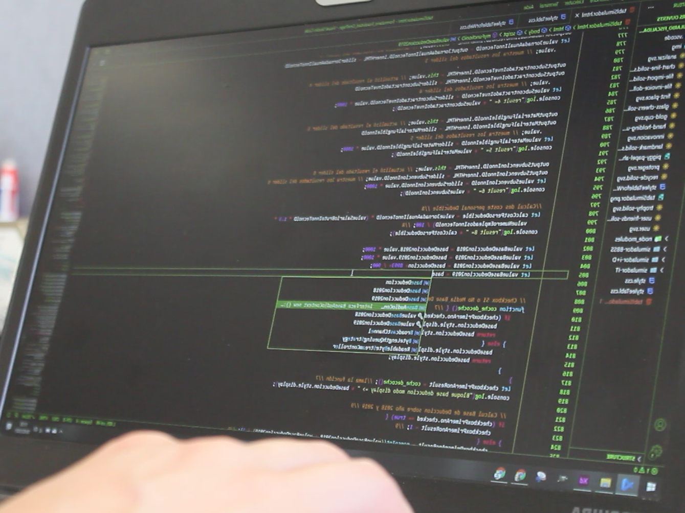 Una persona está escribiendo en una computadora portátil con un montón de códigos en la pantalla