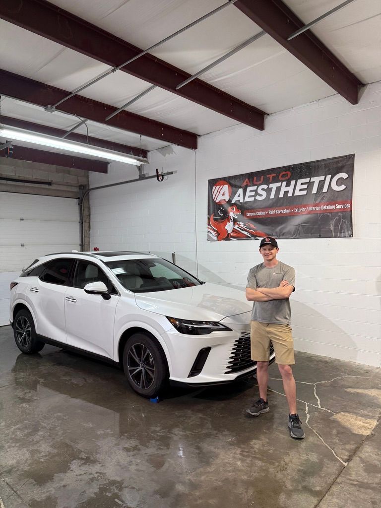 Man standing next to a white Lexus SUV in a garage, with