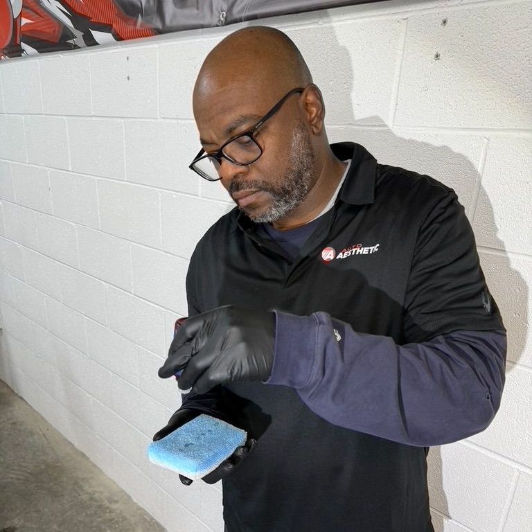 Man in black gloves and shirt, cleaning with blue sponge, in a basement setting.