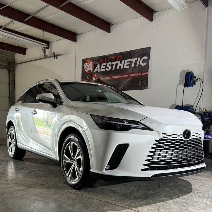 A white car is parked in a garage next to a sign that says auto aesthetic.