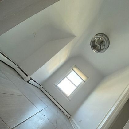 Interior view of a room with a window, ceiling light, and tiled floor, likely a bedroom or closet.