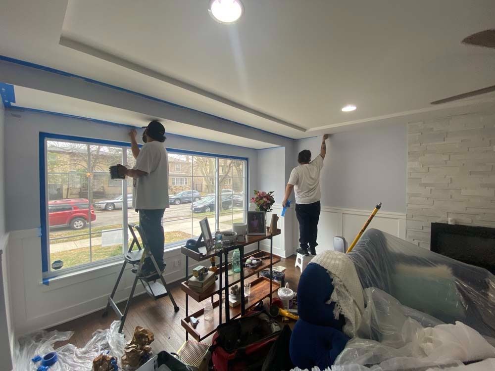 Two people painting a room. One on a ladder, the other on a platform.