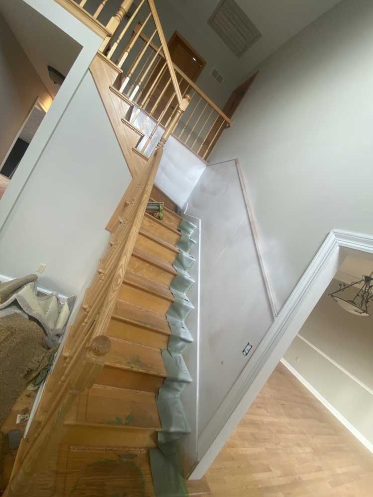Wooden staircase with railing leads to upper level. Walls are painted light gray.
