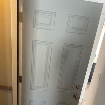 Light gray six-panel door slightly ajar, set in a white door frame.