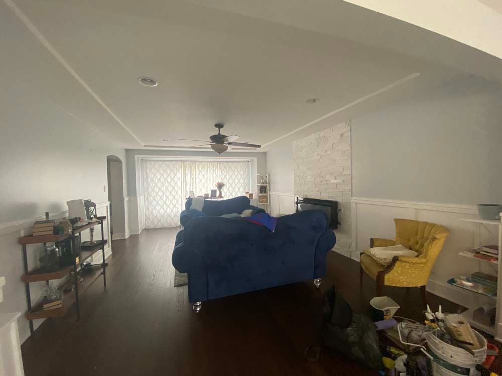 Living room with blue sofa, yellow chair, dark wood floor, and large white map on wall.