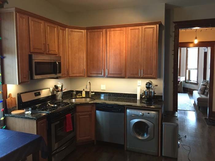 Kitchen with wood cabinets, black countertops, stainless steel appliances, and a washing machine.