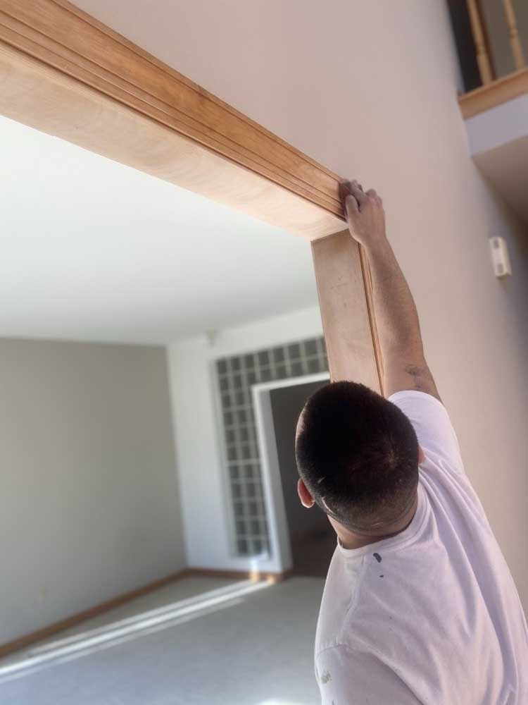 Person installing wooden trim on a doorway.