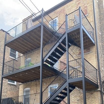 Black metal fire escape on a brick building, with wooden platforms and railings.