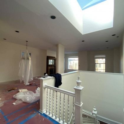 Interior room with a skylight, freshly painted walls, and a staircase. Construction materials are visible.
