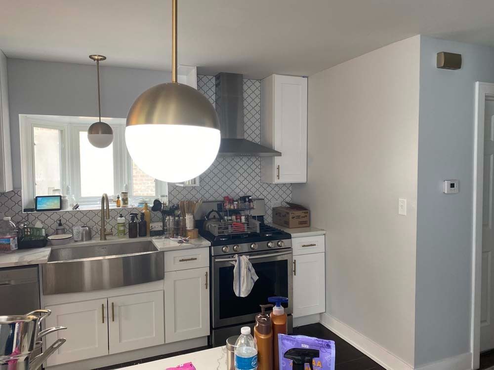Kitchen with white cabinets, stainless steel sink, and globe pendant lights.