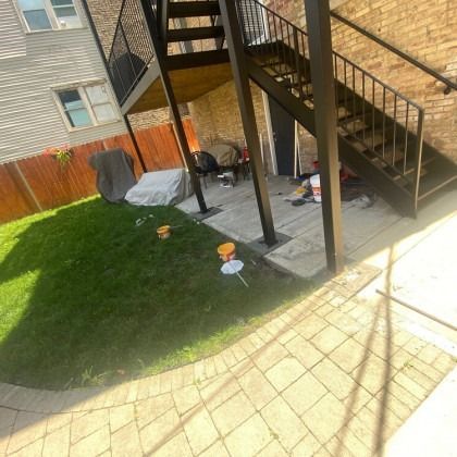 Backyard with grass, patio, and stairs leading to upper levels.