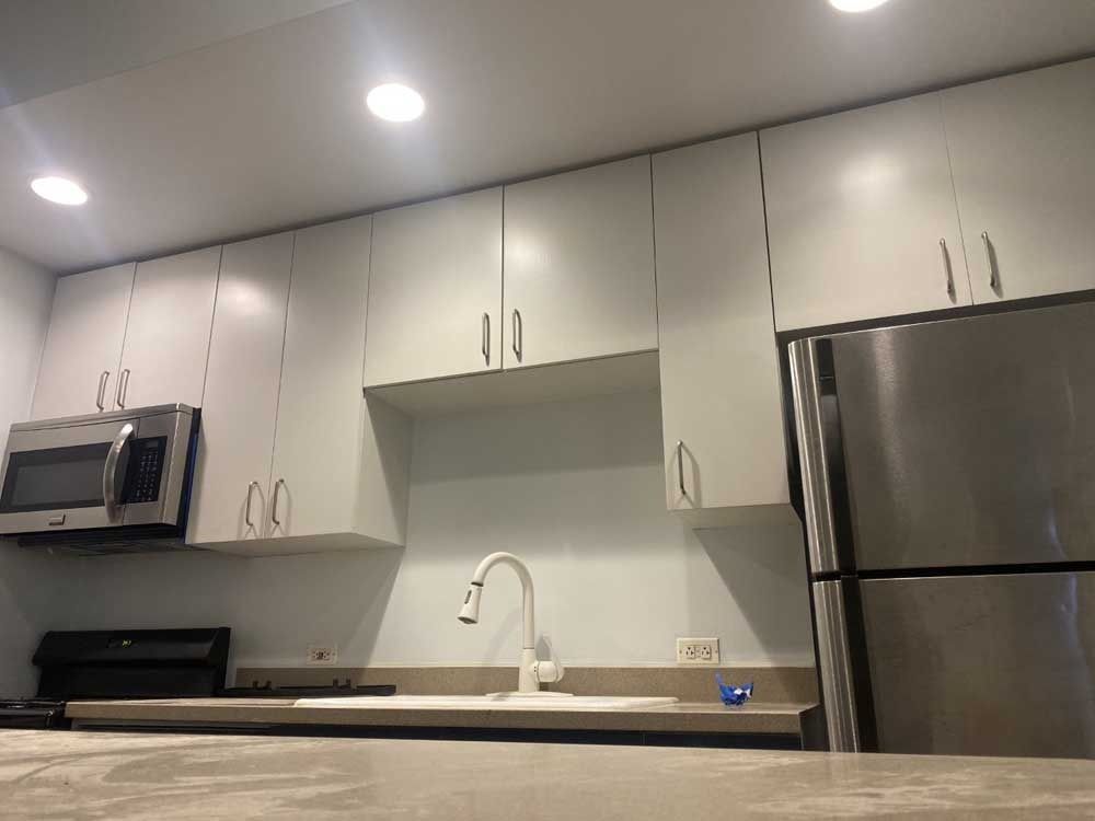 Kitchen with light gray cabinets, stainless steel appliances, and white faucet.