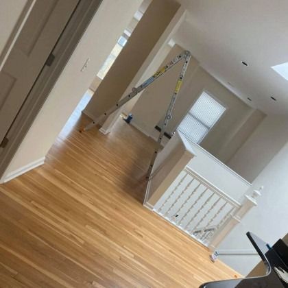 A-frame ladder set up in a home with hardwood floors, near a staircase, and next to a piano.