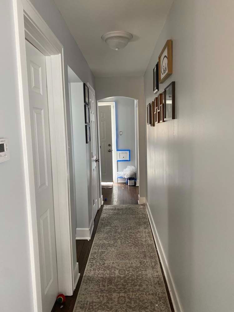 Narrow hallway with white doors, light gray walls, and a patterned rug.