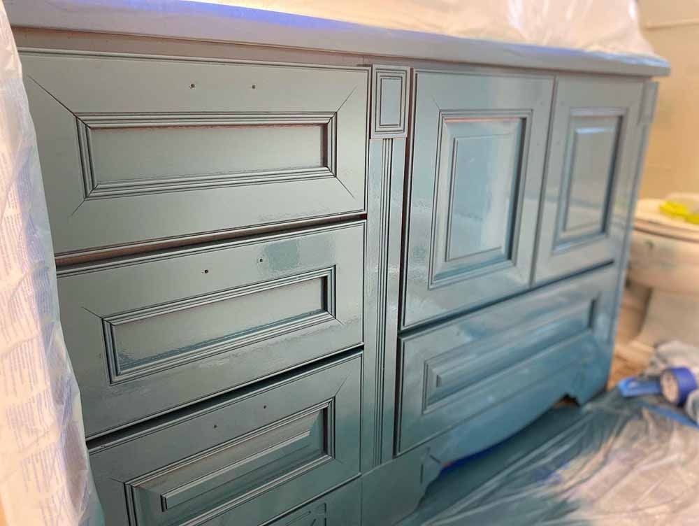 Blue painted bathroom vanity, partially covered with plastic.