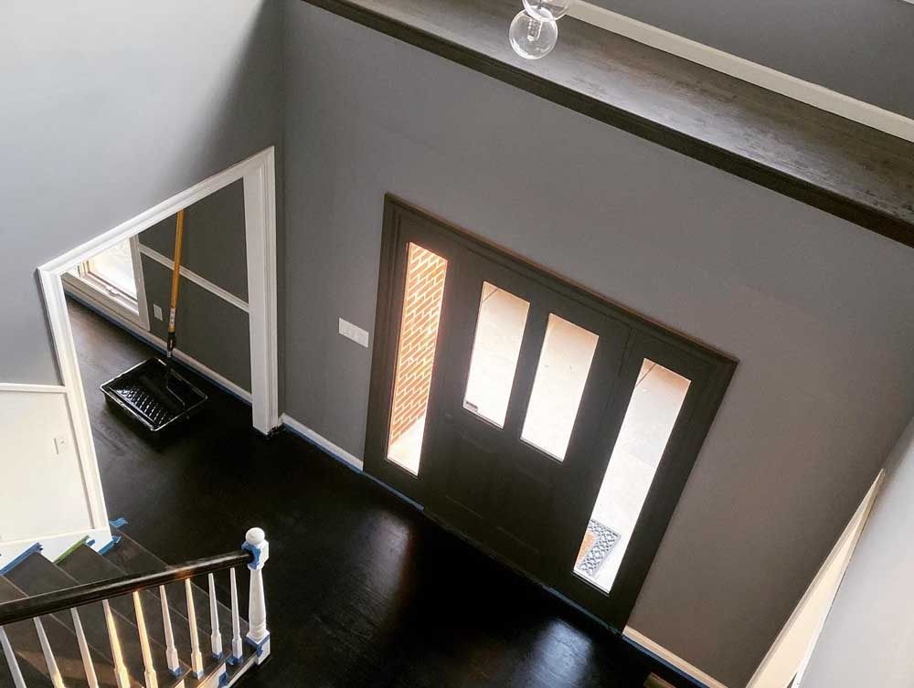 Overhead view of a modern entry with dark gray walls, black door with window panels, and dark hardwood floors.