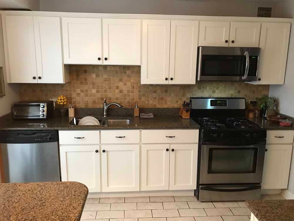 White kitchen cabinets, stainless steel appliances, and a tiled backsplash.