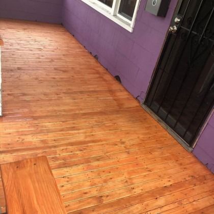 Wooden porch with purple wall, door, and a white-framed window.