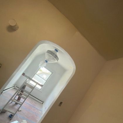 Interior painting in progress; archway, ladder, drop cloth, and unfinished ceiling.