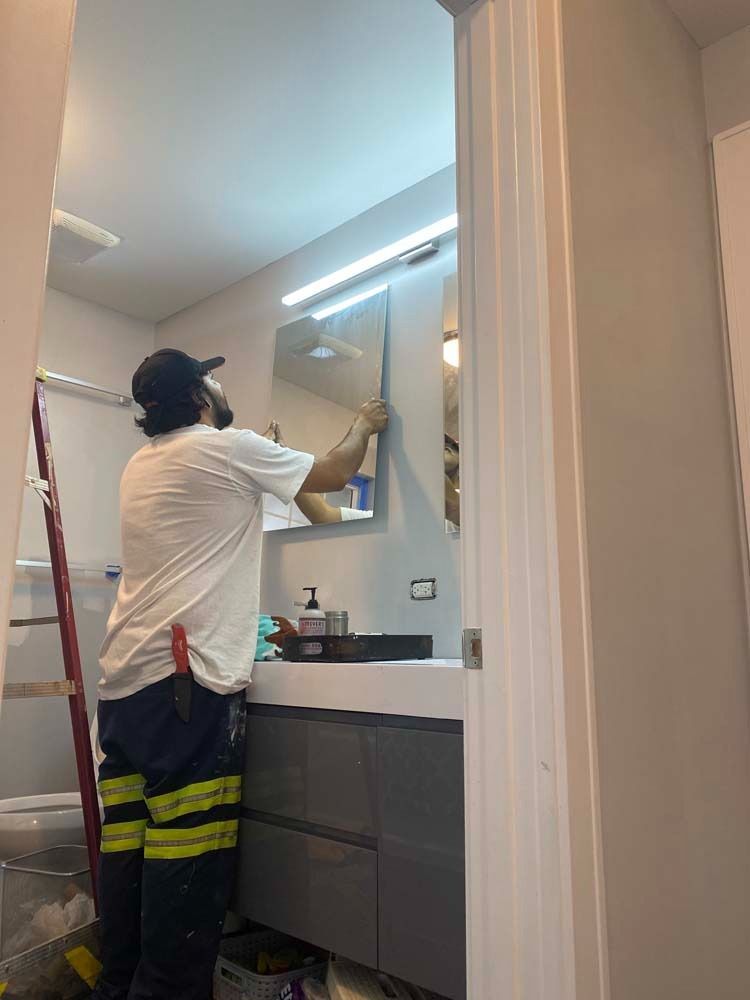 Person installs a mirror in a bathroom with a modern vanity.