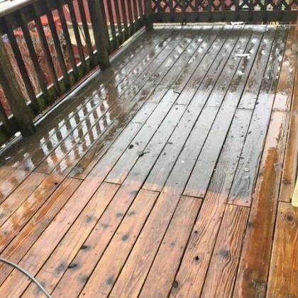 Wet wooden deck after cleaning, showing the contrast between cleaned and uncleaned sections.