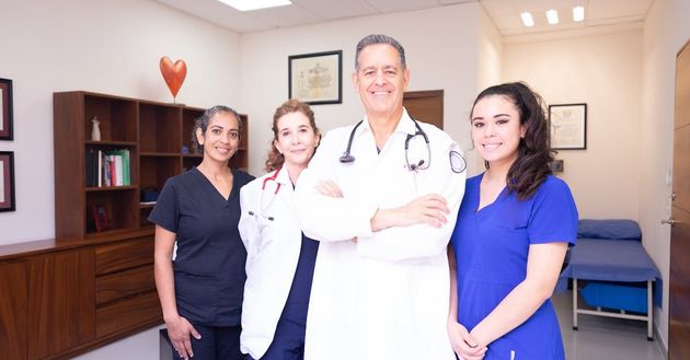 A group of doctors and nurses are posing for a picture in a hospital room.