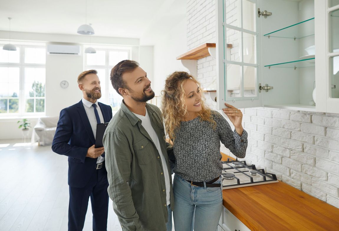 A man and a woman are looking at a kitchen with a real estate agent.