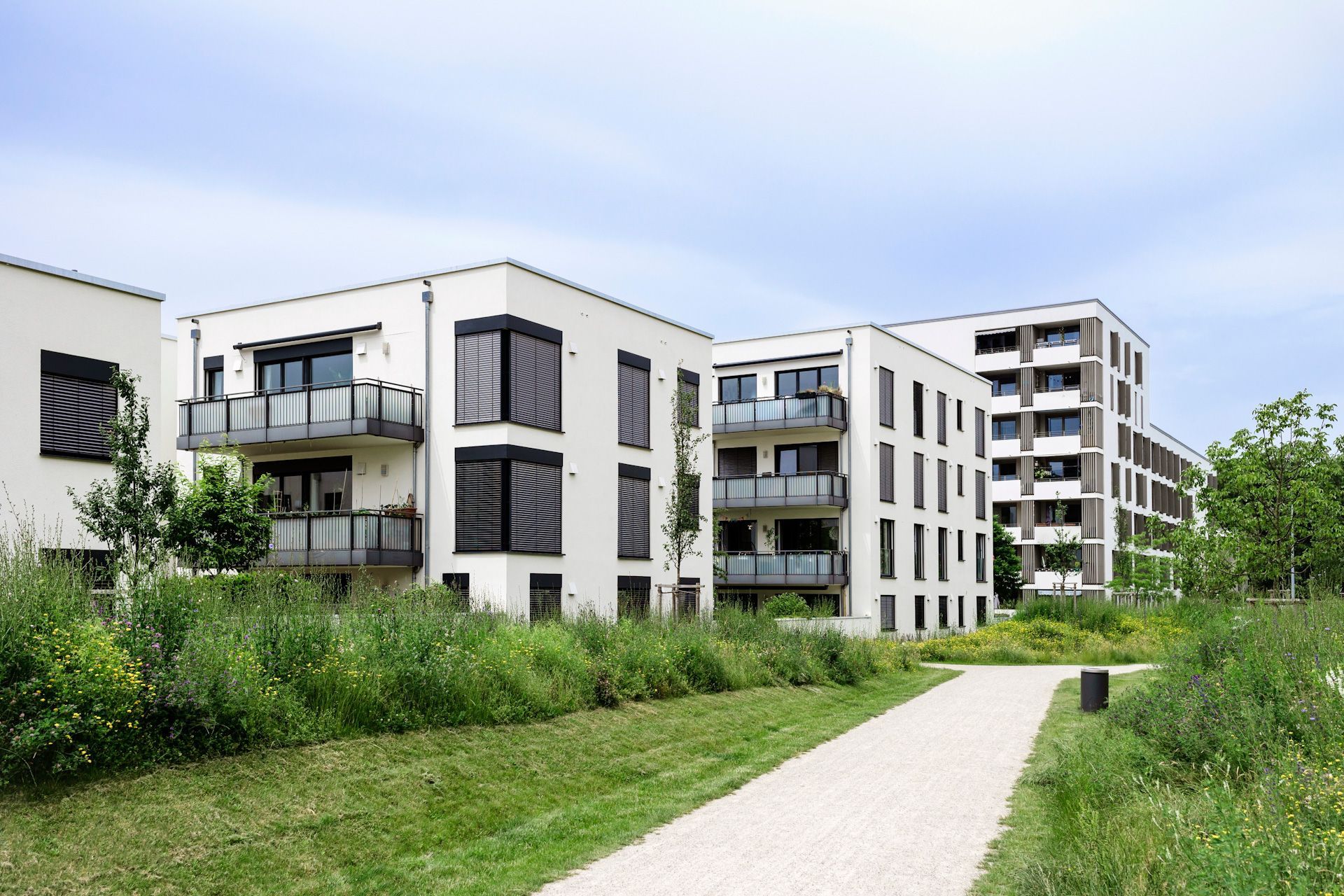 A row of apartment buildings in a residential area with a path leading to them.