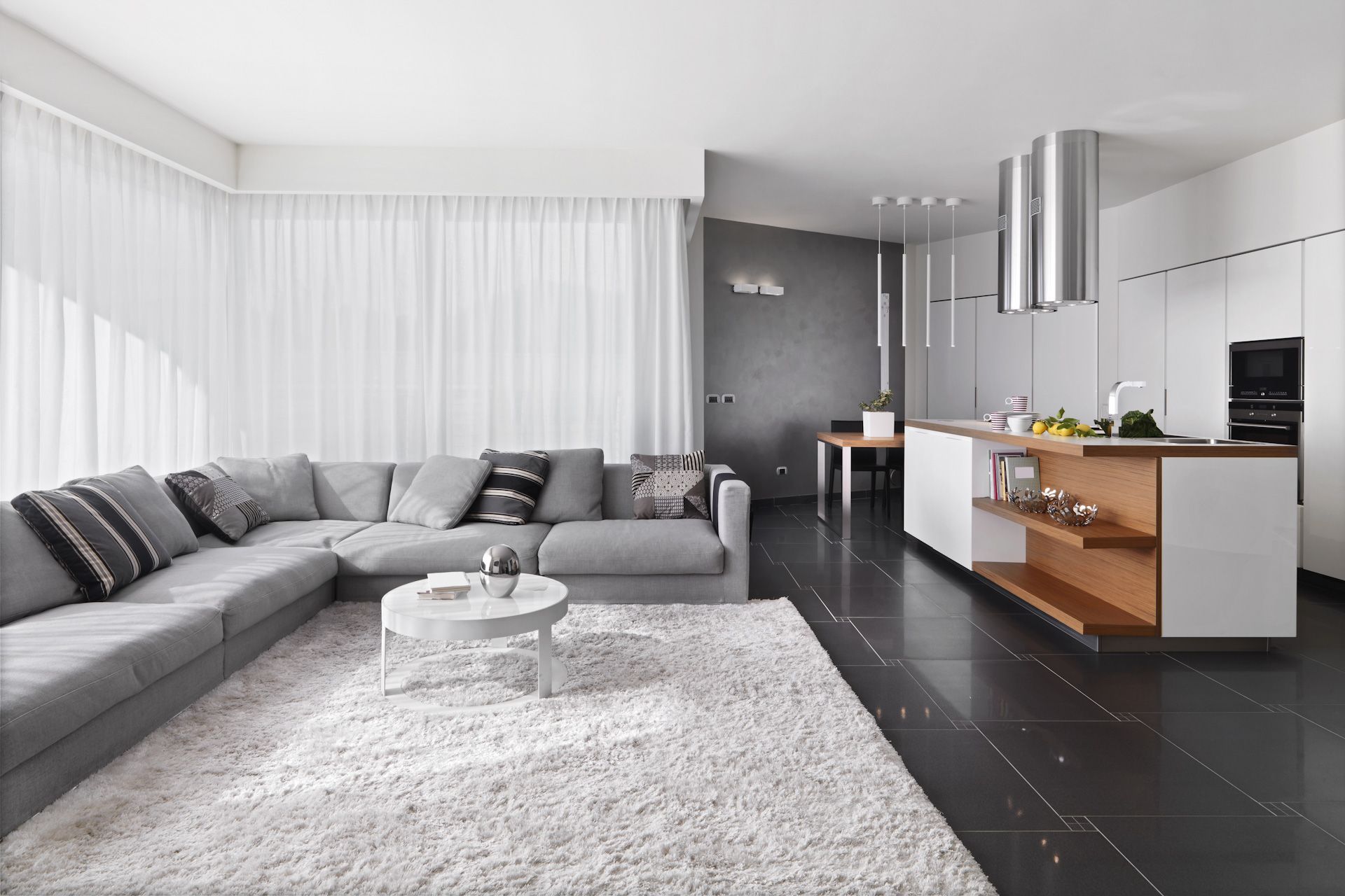 A living room with a gray sectional couch and a white rug
