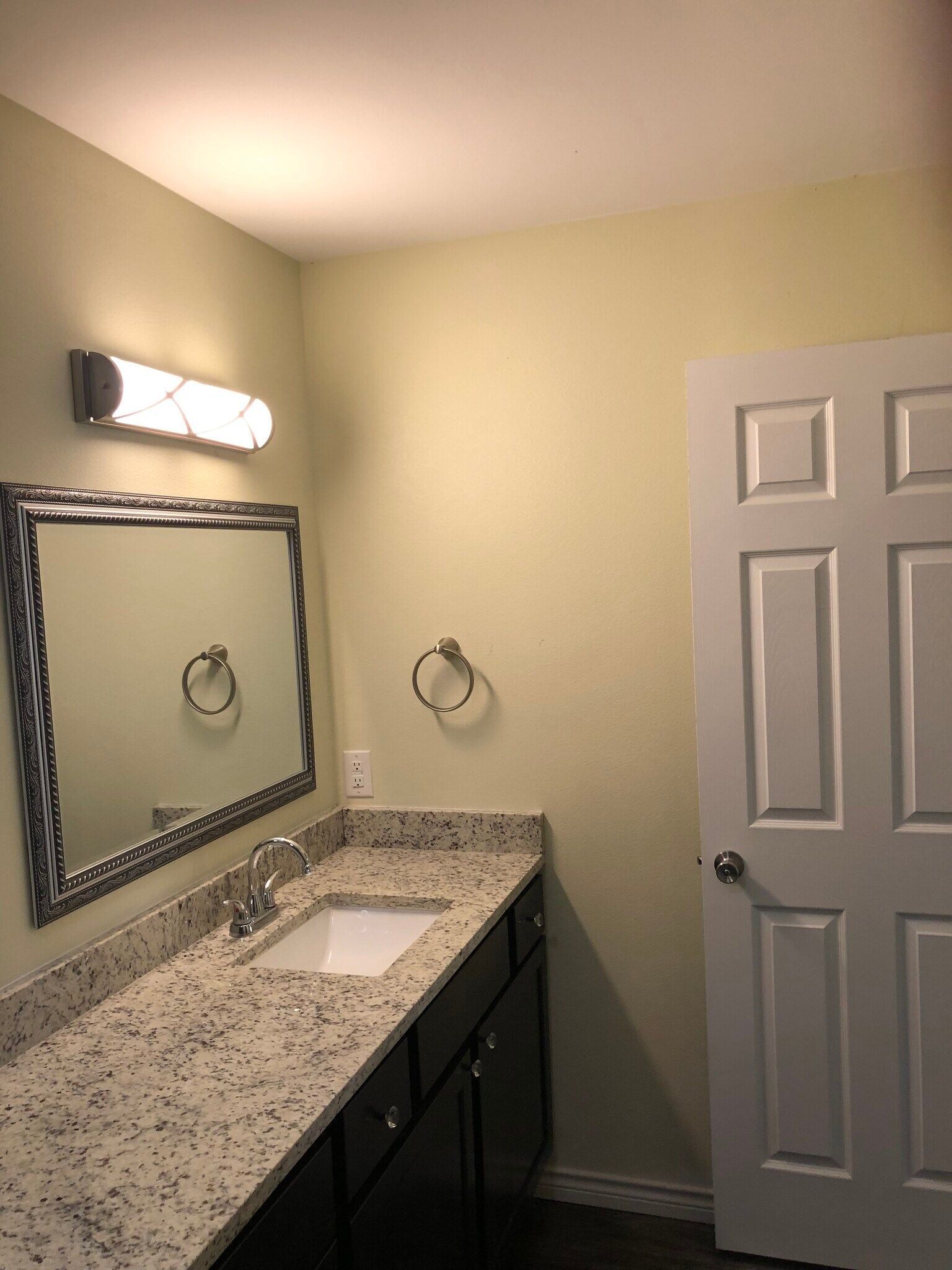 A bathroom with a sink , mirror and door.
