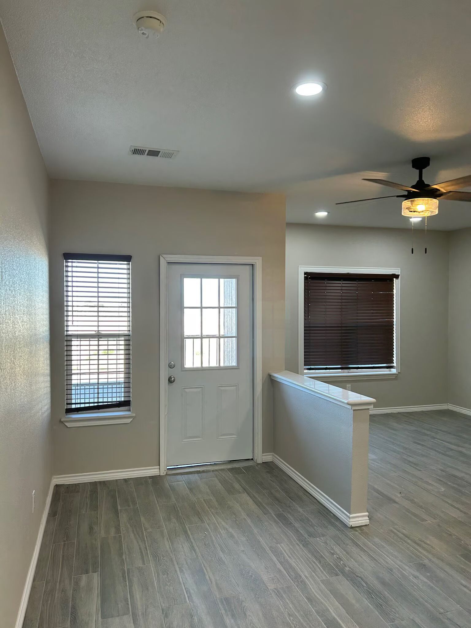 An empty living room with hardwood floors and a ceiling fan.