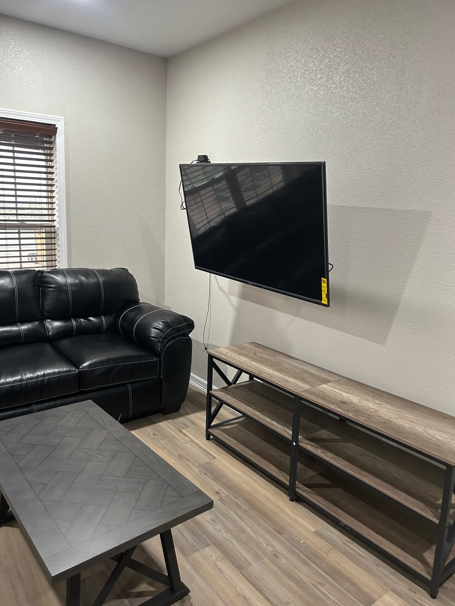 A living room with a couch , coffee table , and television mounted to the wall.